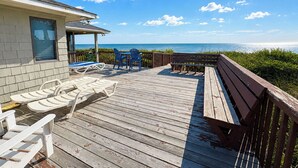 A wooden deck with lounge chairs and a table, overlooking a body of water. - 12 ON 12 - Sip coffee and take in the beautiful ocean views with this oceanfront home! (Southern Shores)