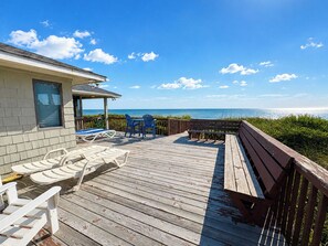A wooden deck with lounge chairs and a table, overlooking a body of water. - Jus' Ducky - Sip coffee and take in the beautiful ocean views with this oceanfront home! (Southern Shores)