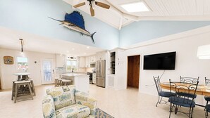 A spacious living area with a dining table, sofa, and a ceiling fan. - 12 ON 12 - Sip coffee and take in the beautiful ocean views with this oceanfront home! (Southern Shores)
