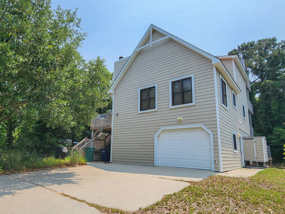 A two-story house with a garage, a covered porch, and a staircase leading to an upper level.