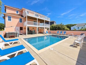 A two-story building with a pool area, including lounge chairs and a hot tub. - Peachy Plover - Oceanside 6 BR Home w/Private Pool & Hot Tub (Duck)