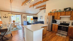 Une cuisine spacieuse dotée de meubles en bois, d’un grand îlot central et d’un coin repas avec une table et des chaises.