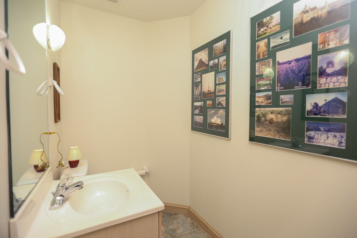 A bathroom with a sink, mirror, and framed pictures on the wall.