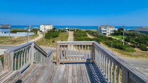 A wooden boardwalk leading to beachfront properties with clear skies.