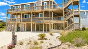A multi-story wooden building with balconies, a central staircase, and a sign indicating availability for rent.