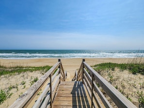 A wooden boardwalk leading to a beach with ocean views.