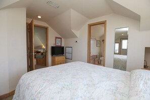 A bedroom with a large bed, a television, a dresser, and a mirror. - Carolina Dreamin' - Oceanfront 5 BR Home with community pool - Dogs Allowed (Duck)