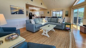 A spacious living room with a sofa set, a coffee table, and a dining table. - “Surf & Sound” is the best of both worlds! Just steps away from the beach and Sound! (Duck)