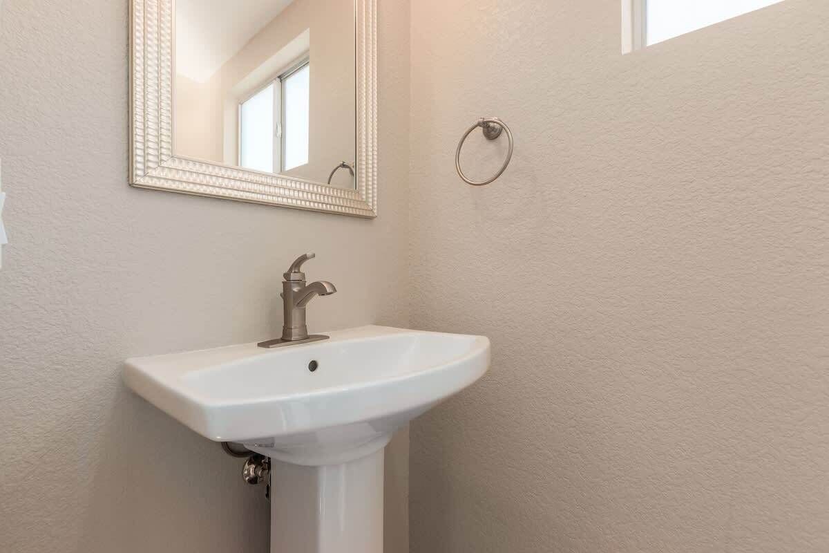 A bathroom with a white sink, a mirror, and a towel ring.