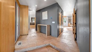 A modern hallway with a stone floor, wooden panels, and a gray wall with a framed picture. - Red Rock-view Sedona retreat with 2 bedrooms, 2 baths, and fireplace. (Sedona)