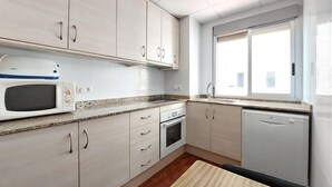Een moderne keuken met witte kasten, een magnetron, een oven en een vaatwasser.