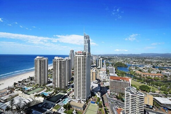 Un paisaje urbano costero con edificios altos, una playa y un puerto deportivo.