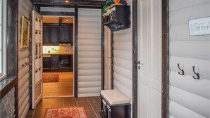 A narrow hallway leading to a kitchen with dark cabinets, a white door, and a shelf with hats. - Gorgeous home in Fyresdal (Fyresdal)