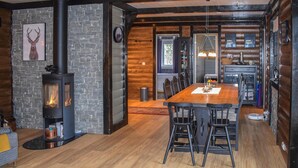 A cozy cabin interior with a central wooden dining table, black chairs, a stone fireplace, and a rustic kitchen area. - Gorgeous home in Fyresdal (Fyresdal)