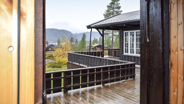 A wooden deck with a railing leading to a building with a dark roof and white windows. - Gorgeous home in Fyresdal (Fyresdal)