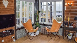 A cozy room with a large window, two leather chairs, a television, and a small table with candles and a lamp. - Gorgeous home in Fyresdal (Fyresdal)