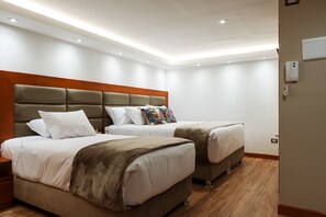 Two single beds with matching headboards and footboards, adorned with white bedding and decorative pillows.
