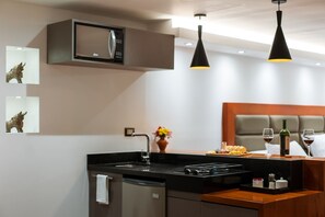 Kitchen area with microwave, sink, and cabinet, adjacent to a cozy bedroom with a bed.