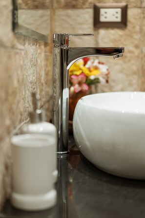 Bathroom features a sleek faucet, white sink, and textured wall.