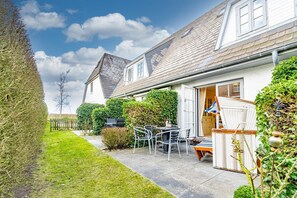 A residential property with a patio, outdoor furniture, and a garden.