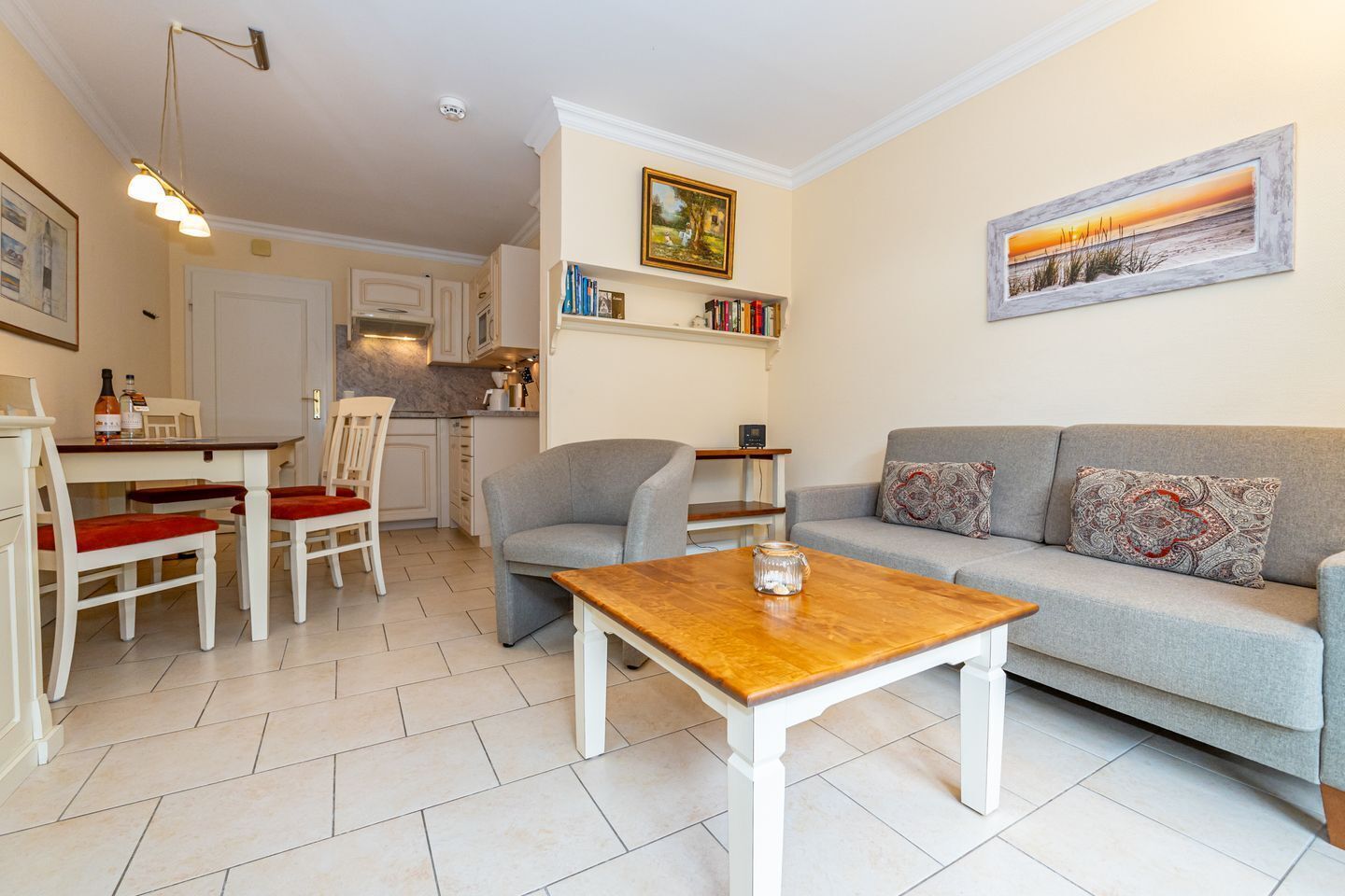 Un salon moderne avec un canapé gris, une table basse en bois et un coin repas comprenant une table blanche et des chaises rouges.