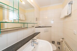A modern bathroom with a glass shelf, a sink, a toilet, and a towel rack.