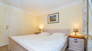 Una camera da letto con un letto grande, due comodini con lampade, una porta e un quadro appeso al muro.