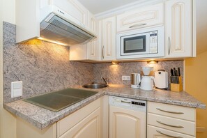 A compact kitchen with white cabinets, a Bosch microwave, a coffee maker, and a dishwasher.
