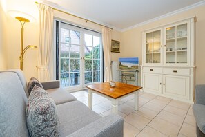Een woonkamer met een bank, een salontafel, een televisie en een kast met glazen deuren.