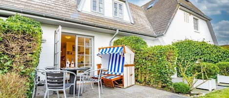 A house with a patio area featuring outdoor furniture and a striped beach chair.