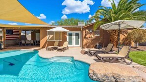 A swimming pool with lounge chairs and a covered area, surrounded by palm trees and a clear sky. - 4BR Scottsdale Tempe Oasis! Heated Pool & Hot Tub! (Tempe)
