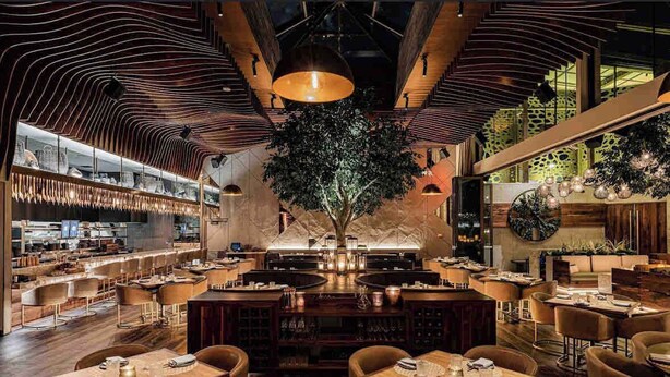 A modern restaurant interior with a central tree, wooden tables, and a bar area. - 4BR Scottsdale Tempe Oasis! Heated Pool & Hot Tub! (Tempe)