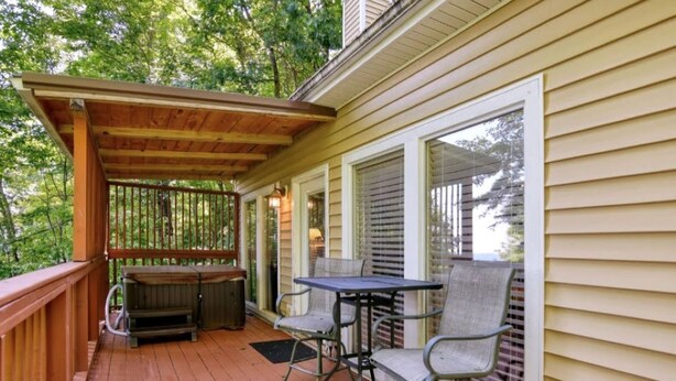 A wooden deck with a covered seating area, a table, and chairs.