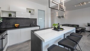 A modern kitchen with a central island, black bar stools, and a grey countertop. - Luxurious home in Mandre (Mandre)