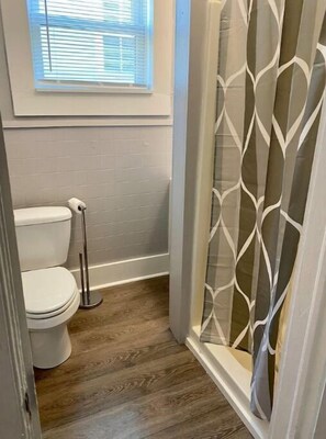 Ein Badezimmer mit Toilette, Duschbecken und einer Dusche mit Glasabtrennung.
