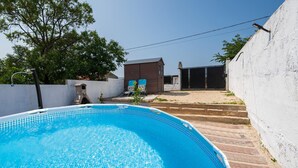 Une piscine agrémentée d’un élément décoratif en pierre, un petit bâtiment et un portail, le tout situé dans un jardin.