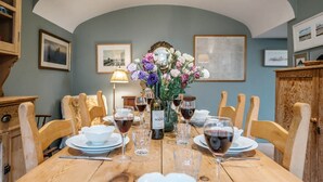 A dining table set for six with wine glasses, a bottle of wine, and a vase of flowers. - 29 Wentworth Road, Aldeburgh (Aldeburgh)