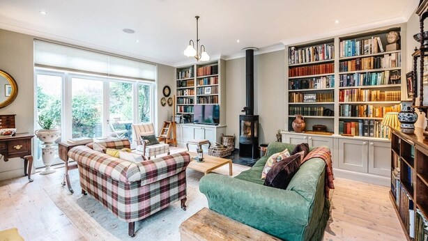 A cozy living room with a fireplace, a green sofa, a plaid sofa, and a bookshelf filled with books. - 29 Wentworth Road, Aldeburgh (Aldeburgh)
