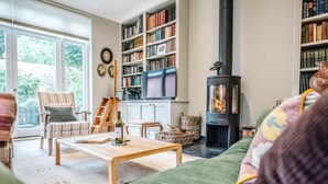 A cozy living room with a fireplace, a bookshelf, and a comfortable seating area. - 29 Wentworth Road, Aldeburgh (Aldeburgh)