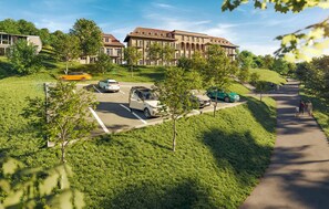 A parking area with multiple cars, a pathway, and a building with a tiled roof.
