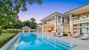 A modern resort with a swimming pool, outdoor seating, and lush greenery.