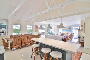 Cozinha espaçosa com uma ilha grande, cadeiras de vime e iluminação pendente.