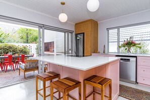Cozinha moderna com uma ilha grande, banquetas de madeira e vista para o exterior.