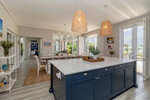 A modern kitchen with a large island, pendant lights, and a view of the outdoors.