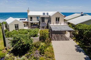 Uma casa moderna com um amplo pátio, painéis solares e vista para o mar.