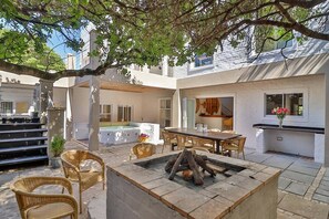 Un patio con hidromasaje, mobiliario exterior y una chimenea.