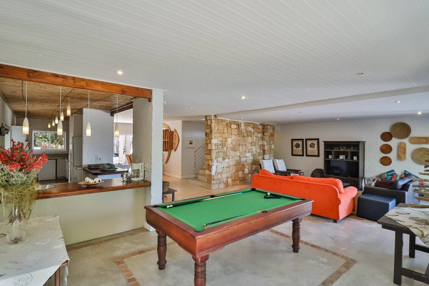 A pool table in a living area with a sofa and a television.