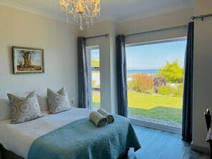 Un dormitorio con una cama grande, un cuadro en la pared y vistas a un jardín por la ventana.
