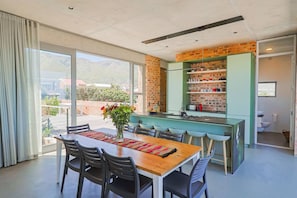 Una cocina moderna con pared de ladrillo, una isla verde y una zona de comedor con mesa y sillas.