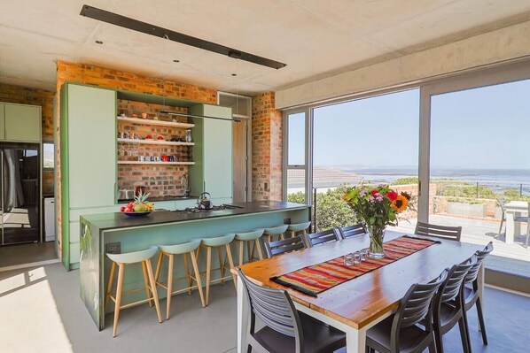 A modern kitchen with a brick backsplash, a bar area, and a dining space with a view of the ocean.